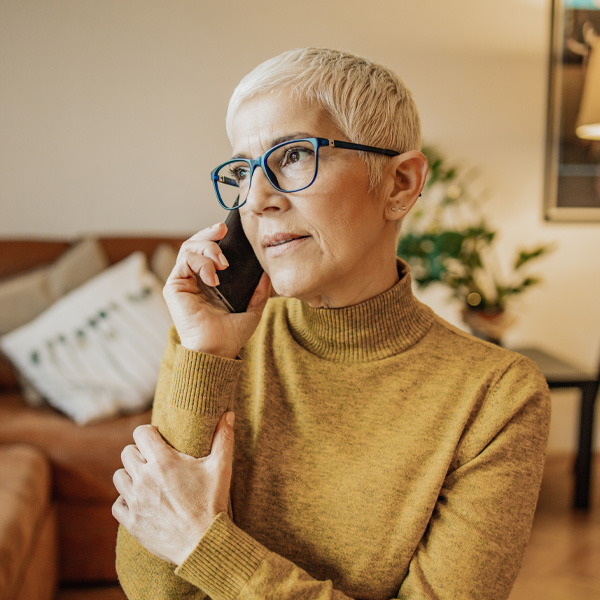 A worried senior woman with short gray hair is talking on the phone