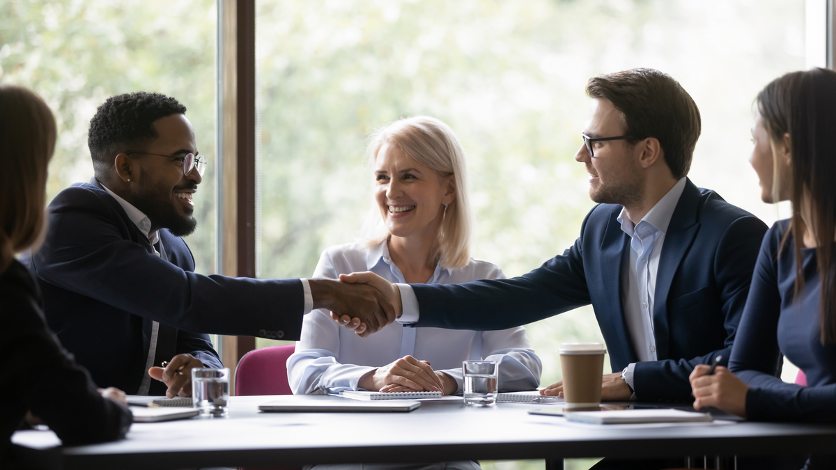  Happy multi-ethnic team members, conference participant, coworkers shaking hands on meeting. Business leader expressing recognition to promoted manager for good job, work achieve, giving handshake