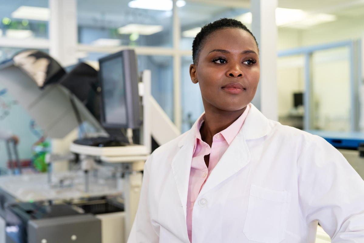 Confident female scientist looking away. Woman doctor wearing lab coat working in medical laboratory.