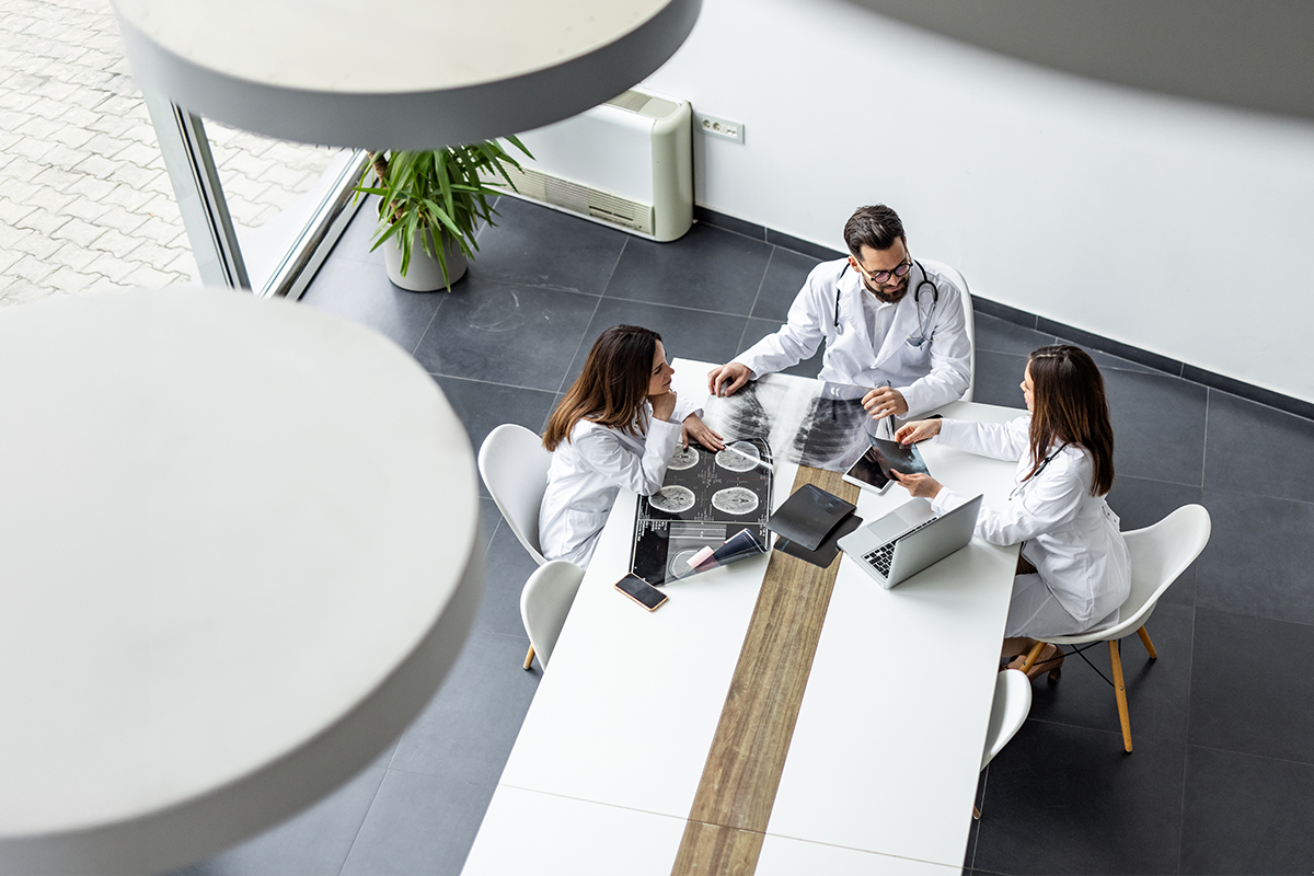 Three providers sitting at a meeting table discussing charts. The photo is from above the table